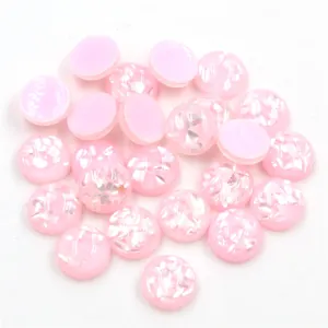 Primo piano di cabochon tondi in resina rosa con glitter e inserti in conchiglia per fai-da-te