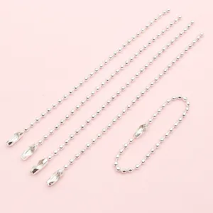 Dettaglio di cinque catenelle a sfere in ferro argentato da 2mm con chiusure su fondo rosa