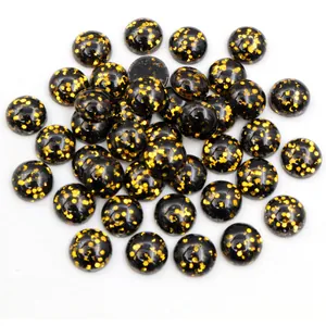 Makroaufnahme schwarzer Harz-Cabochons mit funkelnden Goldpailletten für DIY-Schmuckzubehör