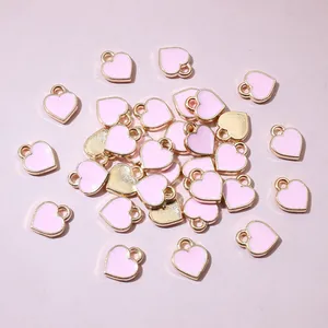 Detailed close-up of mini pink enamel heart charms with gold metal bases for DIY jewelry