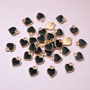 Flat lay of mini gold heart charms with black enamel filling for DIY jewelry making