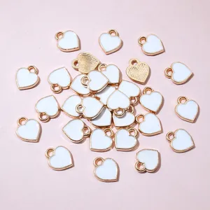 Flat lay of mini white heart charms with gold metal base for DIY jewelry making