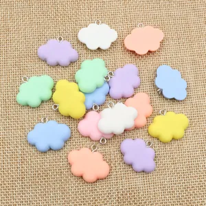 Macro shot of colorful resin cloud charms with metal rings on rustic linen background