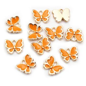Detail von 11 orangefarbenen Emaille-Schmetterlingsanhängern mit Goldrand für DIY-Schmuck