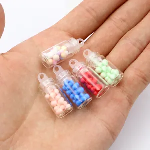 Mini pearl milk tea bottle charms in five colors held in hand for DIY craft projects