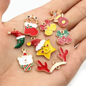Pendentifs de Noël colorés en alliage avec rennes et cloches tenus dans la main