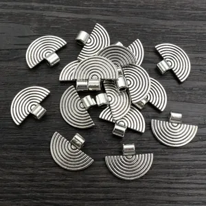 Group of vintage silver fan-shaped metal pendants for DIY jewelry on wood background