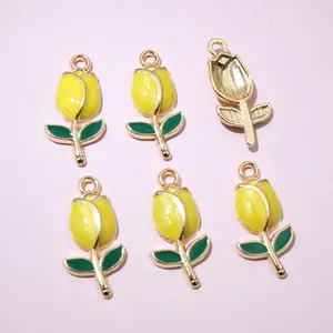 Macro view of six yellow tulip alloy charms with dark green leaves on pink background