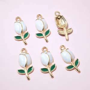 Detailed view of six DIY gold tulip charms with white enamel petals and green leaves