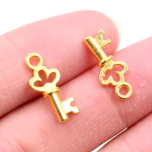 Zwei goldene Schlüsselanhänger aus Legierung mit Kleeblattmuster auf Fingerspitzen