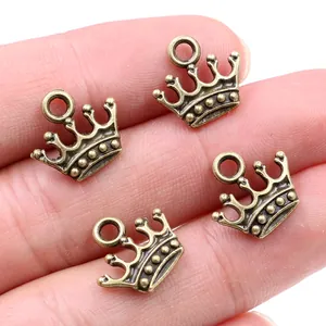 Vier Vintage-Kronenanhänger aus Bronzelegierung für Schmuck, auf dem Finger gezeigt
