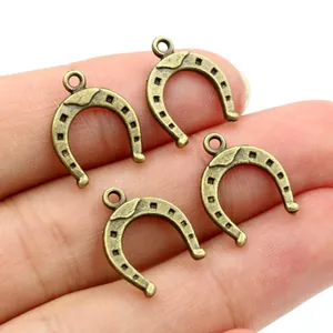 Close-up of four antique bronze horseshoe charms held in hand for jewelry making