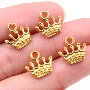 Makroaufnahme von vier kleinen goldenen Kronenanhängern aus Legierung auf einer Hand