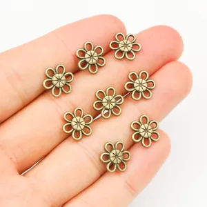 Acht bronzene hohle Blumengestaltung-Anhänger für DIY Schmuckherstellung auf einer Hand
