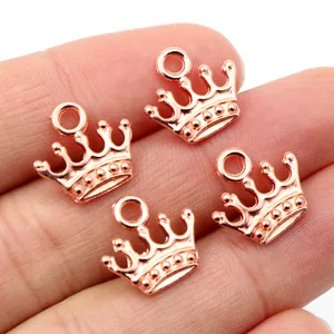Vier roségoldene Kronenanhänger für DIY-Schmuck in der Hand zur Größenansicht gezeigt