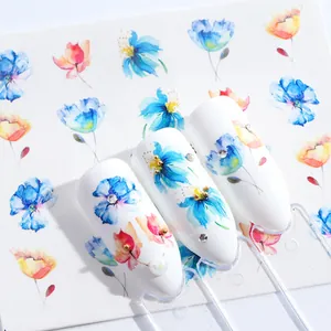 Macro-opname van bloemen nagelstickers in blauw en roze met gouden kralen accenten