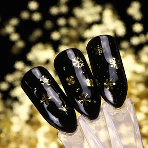 Détail de bijoux d'ongles flocons de neige en métal doré sur vernis noir brillant