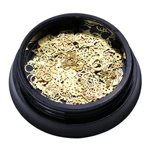 Macro view of gold metal nail art charms including stars and bells in a black round jar