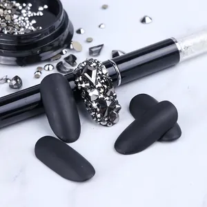 Detailed view of matte black fake nails with sparkling silver geometric rhinestones