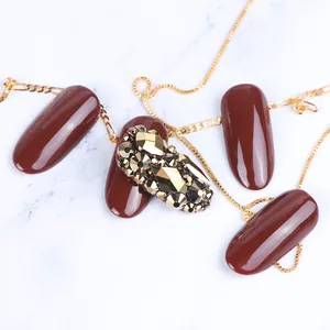Detailed view of burgundy nails with luxury gold rhinestone and crystal embellishments