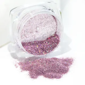 Macro shot of pink purple holographic nail glitter powder pouring from a clear jar
