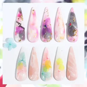 Press-on nails featuring real dried flowers, gold foil marble art, and stiletto shape