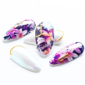 Dettaglio degli adesivi per unghie floreali viola e bianco perlato con accenti dorati