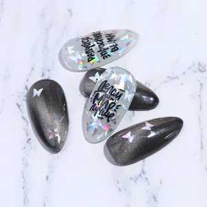 Détail macro de faux ongles amande avec paillettes papillon laser et effet œil de chat