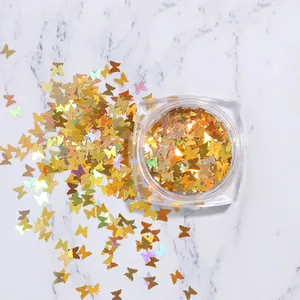 Vue macro de paillettes dorées en forme de papillon pour ongles sur marbre blanc