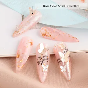 Abalorios para uñas de mariposa 3D oro rosa con textura de mármol y detalles de pan de oro