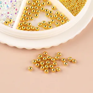 Gros plan de perles dorées et de strass AB irisés dans une boîte de rangement blanche