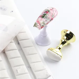 Macro detail of white nail adhesive putty strips with crown display stand and art nail tip
