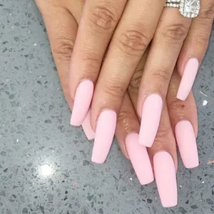 Gros plan d'ongles en forme de cercueil rose clair mat avec finition givrée douce