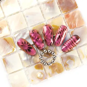 Detalle de uñas magnéticas rosa con herramienta magnética circular sobre baldosa