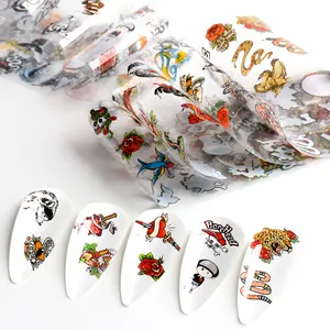 Dettaglio di adesivi colorati per nail art con motivi tattoo old school su unghie bianche