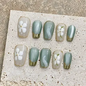 Handmade sage green and creamy white press-on nails with floral art and 3D gold details