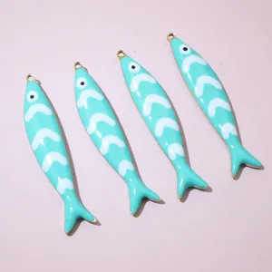 Detailed macro view of four mint green enamel fish charms with gold-plated metal edges