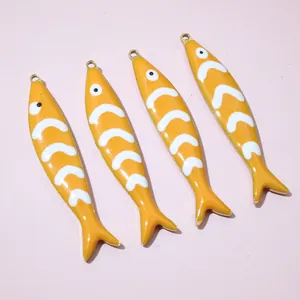 Macro detail of four orange fish enamel charms for DIY jewelry making accessories