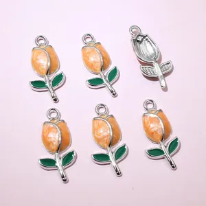 Detail of tulip pendants in orange and green enamel with silver metal frames for DIY crafts