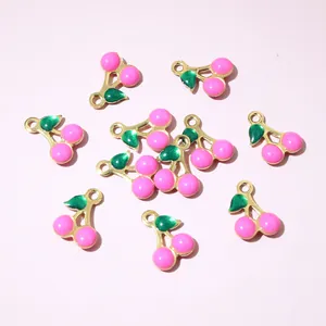 Detail of pink and green cherry charms with gold plating for DIY jewelry making