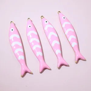 Close-up of four pink enamel fish charms with golden finish for DIY jewelry making