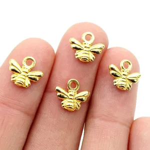 Miniatur Goldene Bienenanhänger für DIY Schmuck auf Fingerspitzen zur Größendarstellung