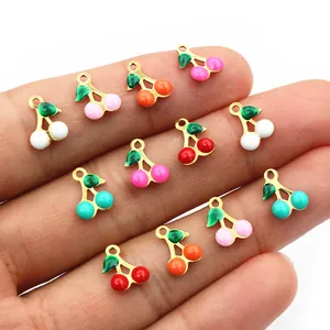 Colorful cherry charms for DIY jewelry making held in hand for scale and detail