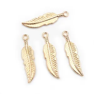 Close-up of four golden alloy feather charms with detailed texture for DIY jewelry making