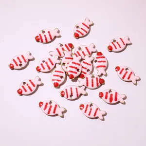 Macro detail of gold-plated fish charms with pink enamel and red stripes for DIY jewelry