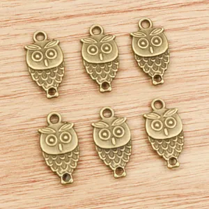 Set of 6 antique bronze owl pendants for DIY jewelry making on a wood background