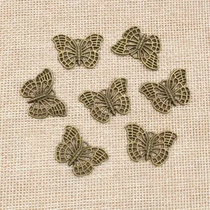Sieben bronzene Schmetterlingsanhänger auf Leinenhintergrund für DIY Schmuckdesign