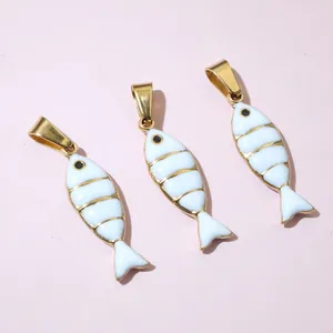 Close-up of three gold-plated small fish pendants with white enamel for DIY jewelry