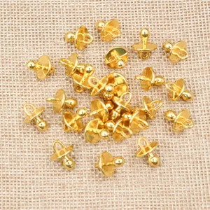 Macro view of gold metal pacifier charms for DIY necklaces on a textured linen fabric