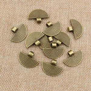 Detailed macro view of vintage bronze fan-shaped alloy pendants on natural beige burlap fabric